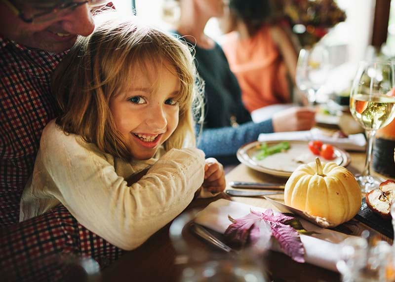 Little girl sitting in father's lap at holiday dinner table